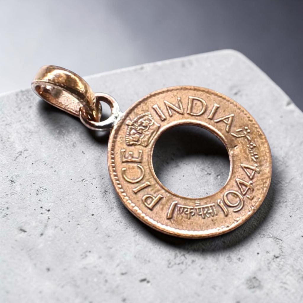 copper coin pendant with 'INDIA' and '1944' on a gray surface