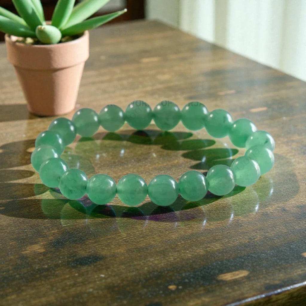 Green Jade bracelet on a wooden surface with a potted plant in the background