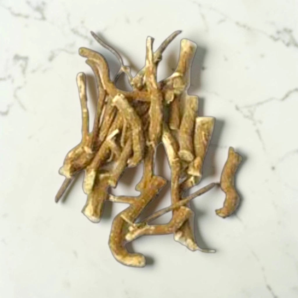 Gold-colored khirni root jadi on a light gray marble surface