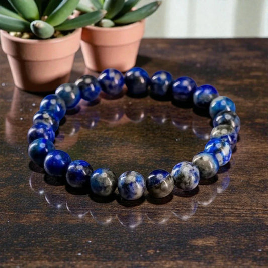 Lapis Lazuli bracelet with Blue stones on a wooden surface with potted plants in the background