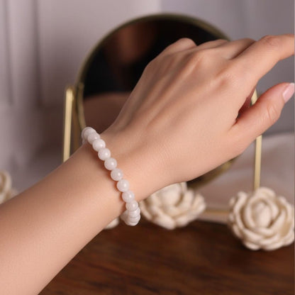 Hand wearing a moonstone-beaded bracelet with a blurred background